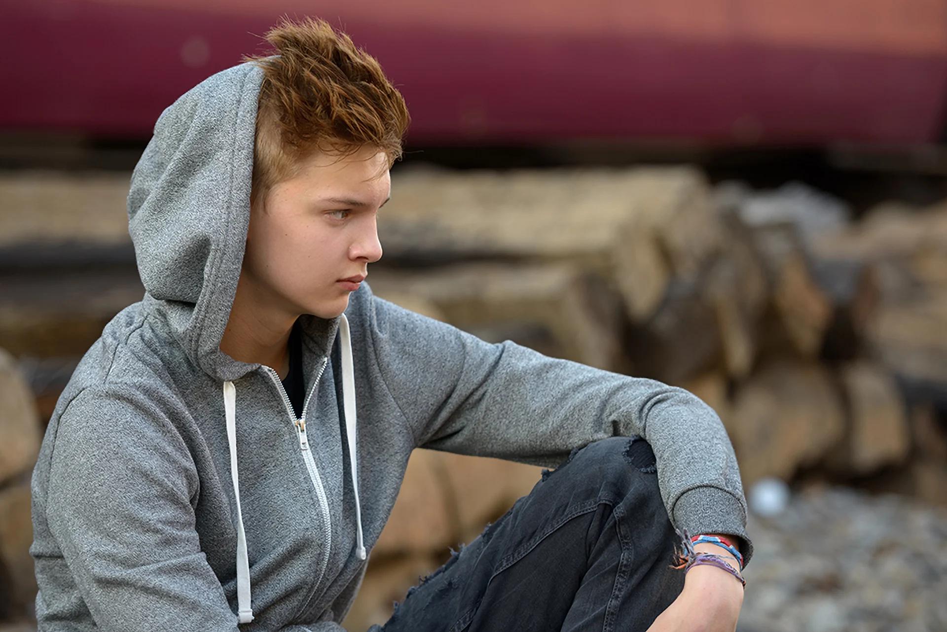 Ein Teenager mit Kaputze auf dem Kopf sieht traurig in die Ferne